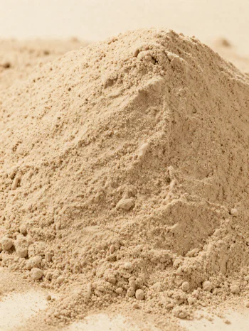 Šviesiai rudi kaštonų miltai kaimiškame dubenyje, išbarstyti ant medinio paviršiaus