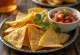 Trikampiai veganiški tortilijų traškučiai dubenėlyje su šviežia salsa