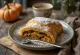 Moliūgų ir aguonų strudelis, iškeptas iki auksinės spalvos, apibarstytas cukraus pudra